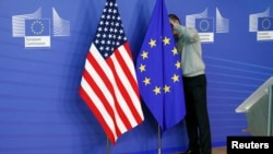 在美国和欧盟的跨大西洋贸易协议谈判初级阶段，有人在调整会场的美国国旗和欧盟旗帜