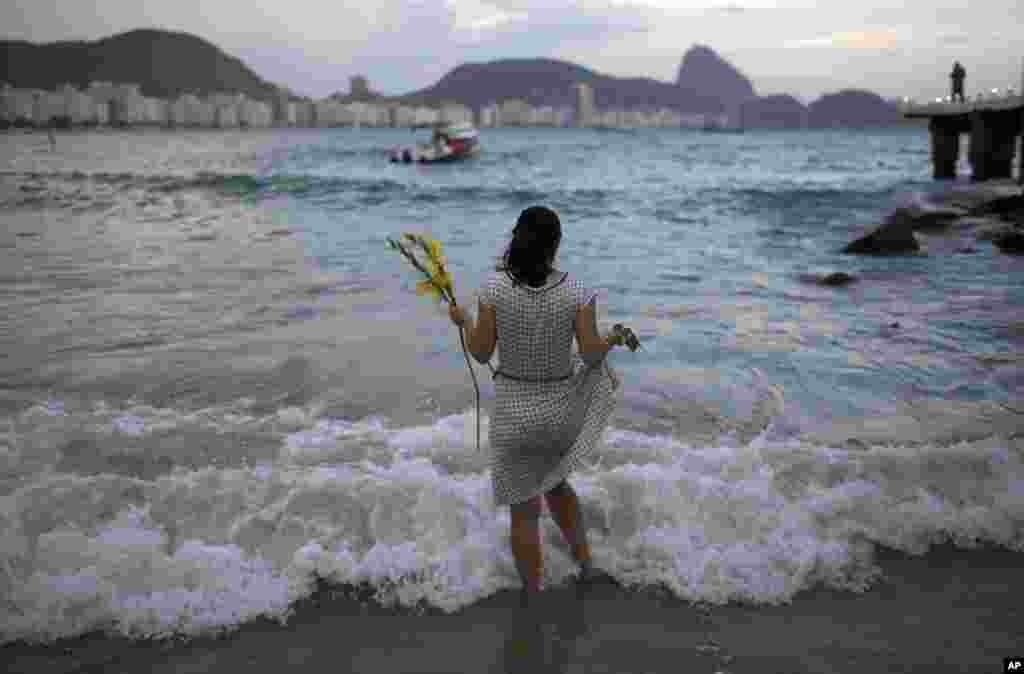 Seorang perempuan memberi persembahan bunga kepada Yemanja, dewi laut, untuk mendapatkan keberuntungan, pada tahun mendatang dalam perayaan Malam Tahun Baru di pantai Copacabana, Rio de Janeiro, Brazil (31/12). (AP/Leo Correa)