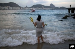 A woman offers flowers to Yemanja, goddess of the sea, for good luck in the coming year during New Year's Eve festivities on Copacabana beach in Rio de Janeiro, Brazil, Dec. 31, 2016.