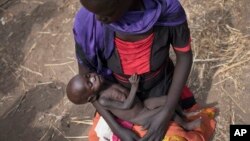 FILE - Adel Bol, 20, cradles her 10-month-old daughter at a food distribution site in Malualkuel in the Northern Bahr el Ghazal region of South Sudan, April 5, 2017.