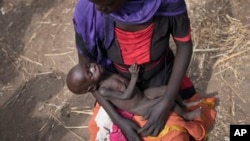 Adel Bol, 20, cradles as she her 10-month-old daughter Akir Mayen at a food distribution site in Malualkuel in the Northern Bahr el Ghazal region of South Sudan.