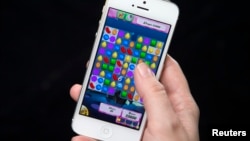 Woman poses for photo illustration with iPhone as she plays Candy Crush, New York, Feb. 18, 2014.
