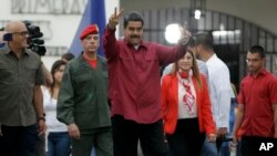 Presiden Venezuela Nicolas Maduro mengacungkan tanda kemenangan "V" (victory) usai memberikan suara di sebuah TPS di Caracas, Minggu (20/5). 