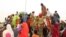 FILE - People, mostly women and children, internally displaced by Boko Haram militants, try to climb a truck protesting food shortages and a diversion of aid supplies meant for them, at a camp in Maiduguri, northeast Nigeria, on June 27, 2019.