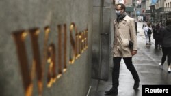 Seorang pria mengenakan masker berjalan di Wall Street di tengah wabah virus corona di Kota New York, 13 Maret 2020. (Foto: Reuters)