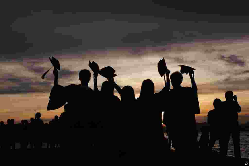 Students wearing their graduation gowns, pose for a photograph during sunset at the Victoria Harbor in Hong Kong.