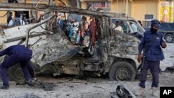 Security forces stand near the wreckage of a minibus at the scene of a car bomb attack in Mogadishu, Somalia, Sept. 28, 2017. 