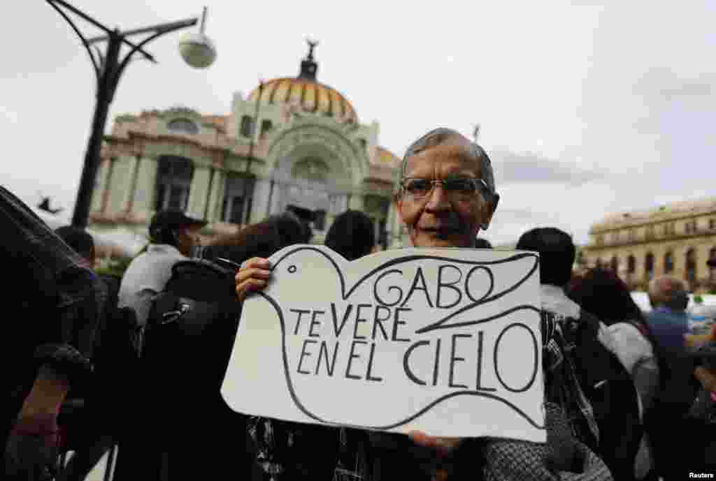 A fan of late Colombian Nobel laureate Gabriel Garcia Marquez holds a sign reading, &quot;Gabo, I see you in heaven,&quot; while standing outside the Palace of Fine Arts for a public viewing of the urn containing the ashes of Garcia Marquez, Mexico City, April 21, 2014.&nbsp;