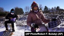 Fourth grader Falis Asair is taking notes about snowflakes during an outdoor class at the Gerald Talbot School, in Portland, Maine. Photo taken on Monday, December 8, 2020. (AP Photo/Robert F. Bukaty)