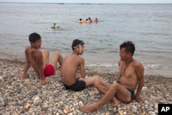 North Korean men chat on a seashore near Mount Chilbo, North Korea, Aug. 20, 2018.