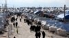 FILE - Women, who lived in the Islamic State's so-called caliphate, walk through al-Hol camp in Hasaka province, Syria, April 1, 2019.