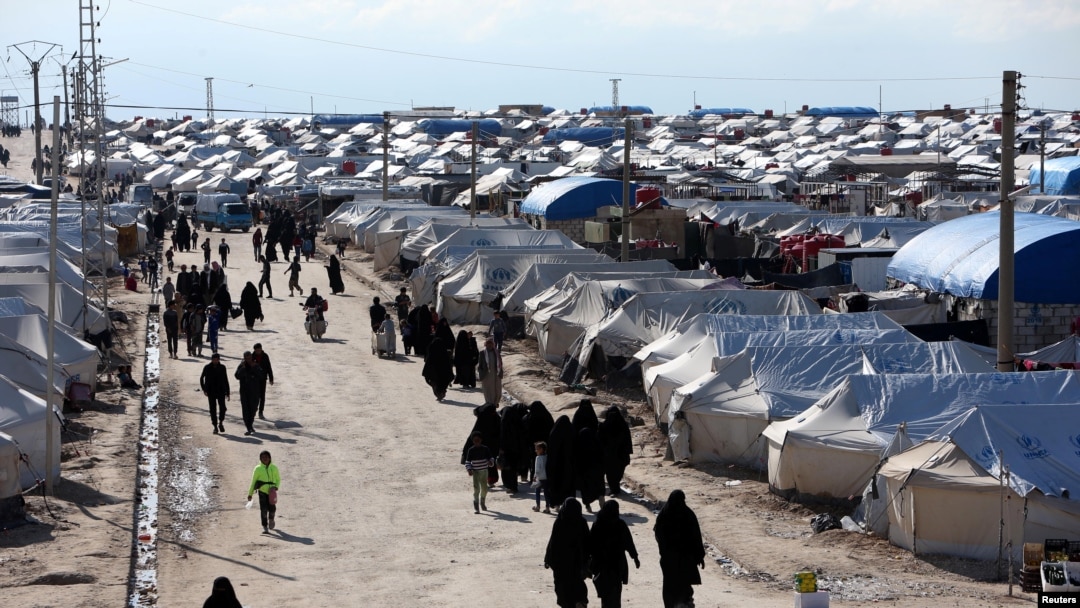 FILE - Women, who lived in the Islamic State's so-called caliphate, walk through al-Hol camp in Hasaka province, Syria, April 1, 2019.