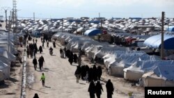 FILE - Women, who lived in the Islamic State's so-called caliphate, walk through al-Hol camp in Hasaka province, Syria, April 1, 2019.