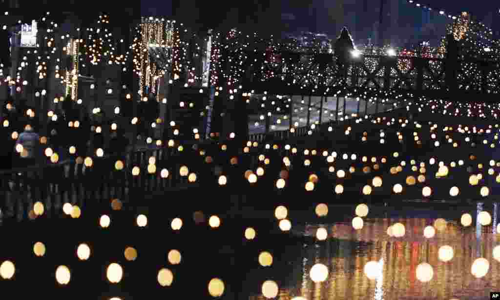 A woman stands on a bridge as Christmas lights illuminate the Darsena dei Navigli, the neighborhood named for the canals that run through this area of Milan, Italy.