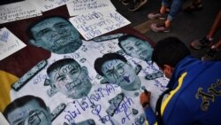 FILE - A protester writes pro-democracy messages on images of Thailand's Prime Minister Prayut Chan-ocha and top Thai generals during an anti-government rally in Bangkok, Feb. 20, 2021.