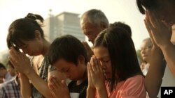Visitors pray for the atomic bomb victims in front of the cenotaph at the Hiroshima Peace Memorial Park in Hiroshima, western Japan, Thursday, Aug. 6, 2015.