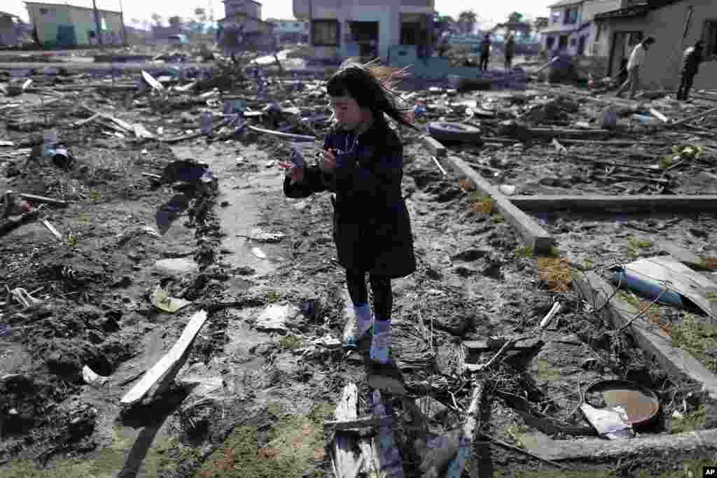 Wakana Kumagai, 7, visits the spot where her house, which was washed away by the March 11, 2011 tsunami, used to stand in Higashimatsushima, Miyagi prefecture, March 11, 2012. (Reuters) 