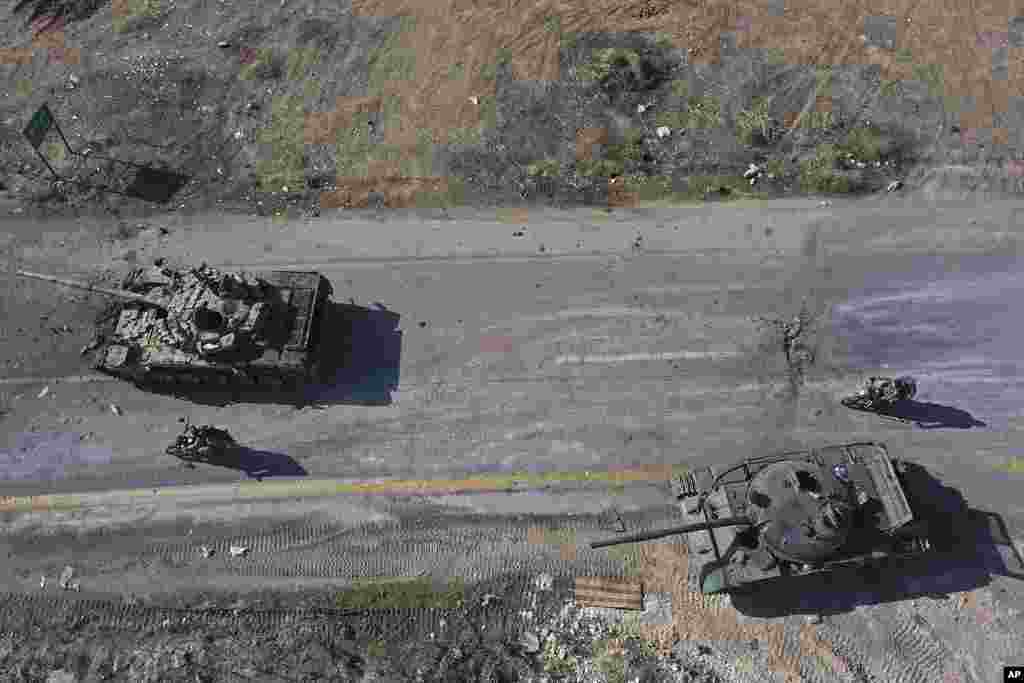 Syrian insurgents ride on motorcycles through abandoned Syrian army vehicles on a road in the outskirts of Hama, Syria.