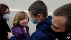 Svetlana Alexievich, the 2015 Nobel literature laureate, second left, looks at a policeman as she arrives for questioning at the Belarusian Investigative Committee in Minsk, Belarus, Aug. 26, 2020. 