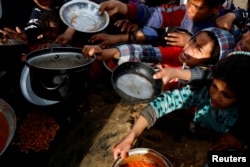 Palestinian children gather to receive food cooked by a charity kitchen, during the Muslim holy month of Ramadan, in Khan Younis, in the southern Gaza Strip, March 3, 2025.