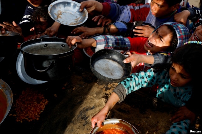 Palestinian children gather to receive food cooked by a charity kitchen, during the Muslim holy month of Ramadan, in Khan Younis, in the southern Gaza Strip, March 3, 2025.