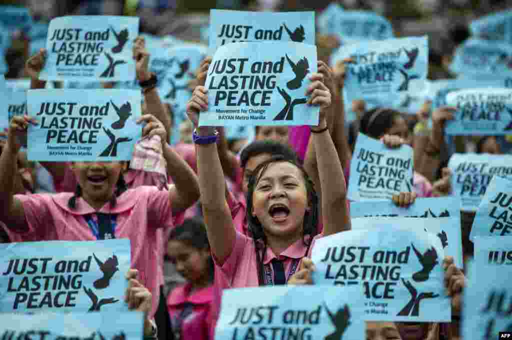 High school students hold signs calling for peace as Philippine President Rodrigo Duterte marks his first 100 days in office in Manila. The group urged Duterte to end crime, drugs, and poverty through peace-building.