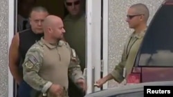 Cesar Altieri Sayoc (in dark shirt), who was arrested during an investigation into a series of parcel bombs, is escorted from an FBI facility in Miramar, Fla., Oct. 26, 2018, in this still image from video. 
