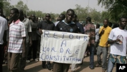 A man carries a sign reading 'Return to constitutional order,' as people gather in protest against the recent military coup, in Bamako, Mali on Monday, March 26, 2012.