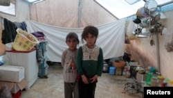 FILE - Syrian siblings, displaced from eastern Idlib province, pose for a picture in a tent at Atmeh camp in Syria, near the Turkish border, June 19, 2020. 