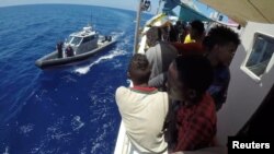 FILE - Migrants are seen on the ship Lifeline while the Malta Armed Forces arrive with aid, near Malta in international waters June 23, 2018, in this still image taken from a video obtained from social media. 