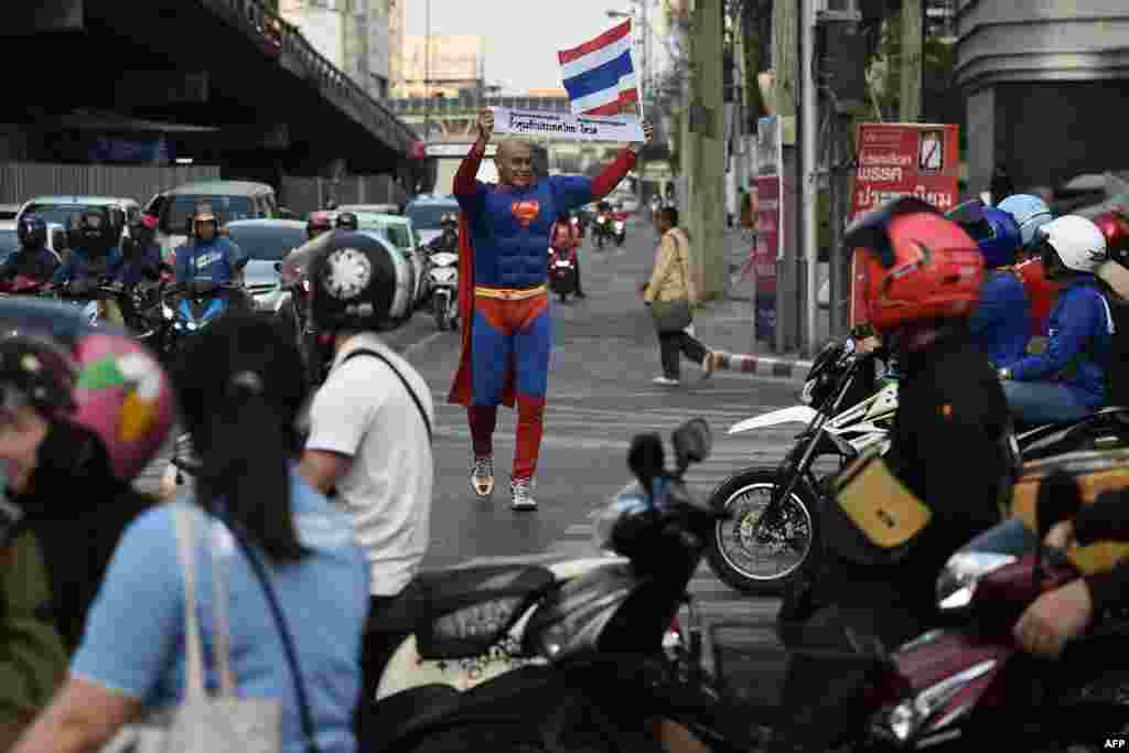 Thai-German national David Pfizenmaier walks through a traffic intersection holding a sign encouraging Thais to vote in the upcoming election in Bangkok, Thailand.