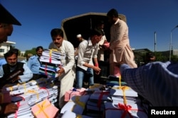 FILE - Employees unload documents before they are distributed for the presentation of the national budget in the National Assembly in Islamabad, Pakistan, May 26, 2017.