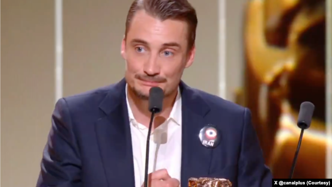 پییر لوتن، بازیگر فرانسوی - روی کت او یک پین با کلمه ایران بود. عکس از «کانال+» تلویزیون فرانسوی