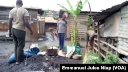 Trois jeunes à côté de leur atelier de fabrication des cocottes en aluminium à Yaoundé, le 16 novembre 2017. (VOA/Emmanuel Jules Ntap)