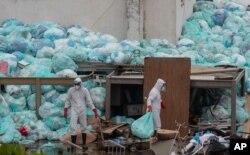 Medical workers dispose of trash bags containing hazardous biological waste into a pile outside the Hospital del Instituto Mexicano del Seguro Social, which treats patients with COVID-19, in Veracruz, Mexico, Aug. 12, 2020.