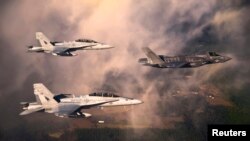 A U.S. Marine Corps F-35 Lightning II multirole fighter jet (R) is escorted by two USMC F-18 Hornets, January 11, 2012. 