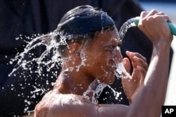 Seorang pria menyiram dirinya dengan air di sepanjang jalan saat suhu panas terus berlanjut di Manila, Filipina pada Jumat, 26 April 2024. (Foto: AP)
