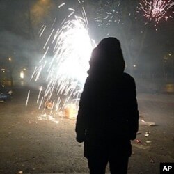 A Chinese woman enjoys the traditional fireworks to celebrate the arrival of the Year of the Rabbit. Fireworks are an old Chinese custom and are used to scare off evil spirits and beckon in good fortune at the start of a New Lunar Year.