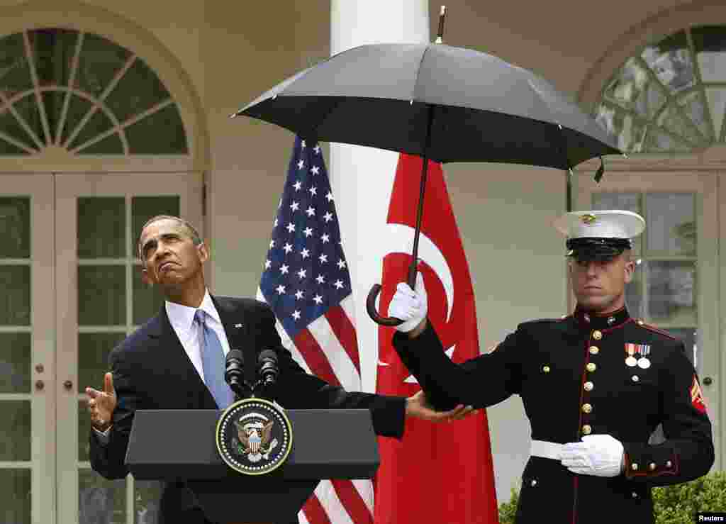 Le président Barack Obama vérifie s'il a toujours besoin d'un parapluie tenu par un marine pour le protéger de la pluie lors d'une conférence de presse avec le président turc à Washington, &nbsp;16 mai 2013.