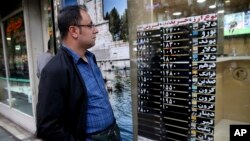 An Iranian checks currency rates at an exchange shop window in downtown Tehran, Iran, Nov. 5, 2018. Iran greeted the re-imposition of U.S. sanctions Monday with air defense drills and a statement from President Hassan Rouhani that the nation faces a "war situation," raising Mideast tensions as America's maximalist approach to the Islamic Republic takes hold. 