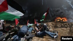 Palestinian demonstrators take cover from Israeli fire and tear gas during a protest against U.S. embassy move to Jerusalem and ahead of the 70th anniversary of Nakba, at the Israel-Gaza border in the southern Gaza Strip, May 14, 2018.