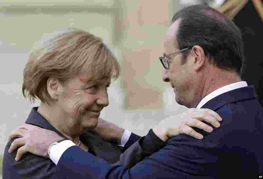 French President Francois Hollande embraces German Chancellor Angela Merkel, left, as she arrives at the Elysee Palace, Paris, Jan. 11, 2015.