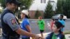 A boy shakes the hand of police officer Anthony Patalena in Fairfax Country, Virginia, Aug. 2, 2016. (D. Block/VOA)