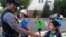 A boy shakes the hand of police officer Anthony Patalena in Fairfax Country, Virginia, Aug. 2, 2016. (D. Block/VOA)