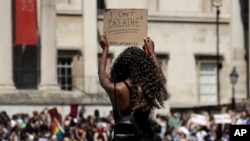 A woman holds up a banner as people gather in Trafalgar Square in central London, May 31, 2020, to protest against the recent killing of George Floyd by police officers in Minneapolis.