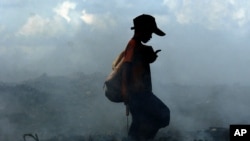 Smoke from burning trash fires swirls around a Cambodian boy as he scavenges a dump on the outskirts of Phnom Penh, file photo. 