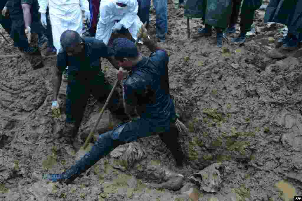 Military rescue workers recover the body of a woman, who was buried alive with scores of others in the October 29 mudslide, at a tea plantation in the central Sri Lankan area of Koslanda. 