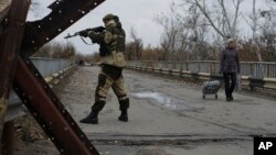 A Russia-backed rebel stands guard on a newly reconstructed bridge which connects rebel controlled territory and government controlled territory in Stanytsia Luhanska, eastern Ukraine. 