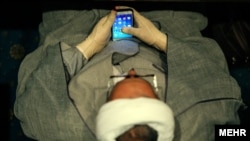 یک آخوند در حال استفاده از اپلیکیش‌های موبایل