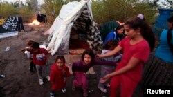 Simona (R), a 11 year-old Roma schoolgirl who has been living in France for 6 years, plays with children near shelters at an illegal camp on the banks of the Var River in Nice, southeastern France, Nov. 6, 2013.